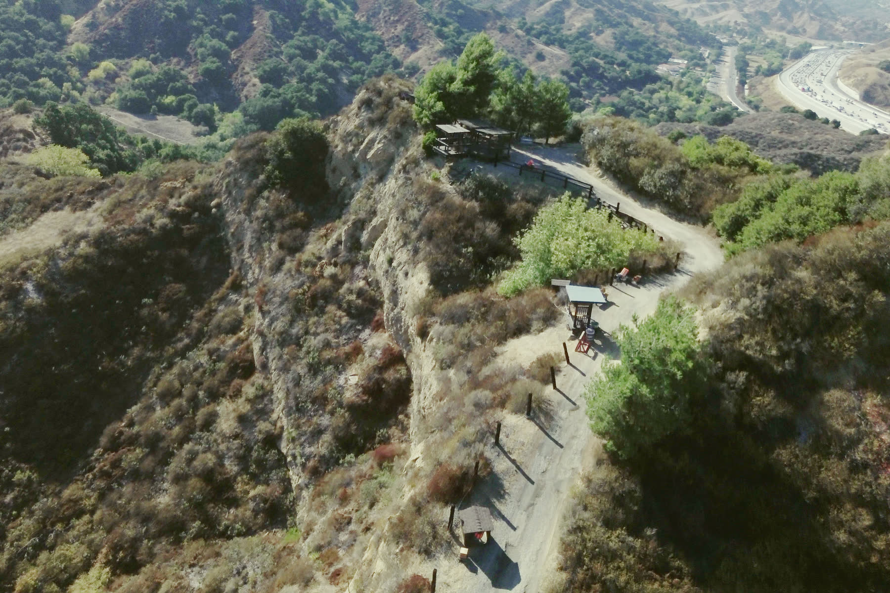The course road along the ridge from the air, a covered stand beside it and the freeway in the valley beyond.