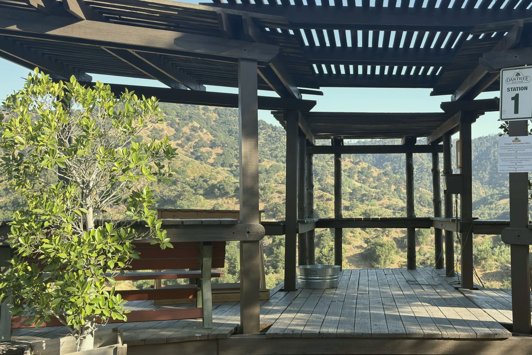 The covered stand at station 1, an oak beside it and the hills beyond.